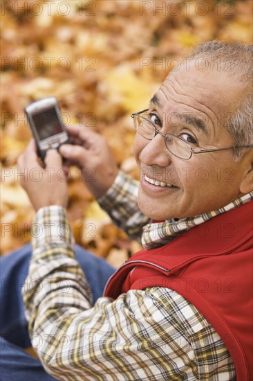 Hispanic man using cell phone outdoors in autumn