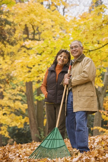 Hispanic couple raking autumn leaves