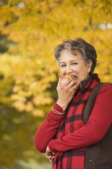 African woman eating apple outdoors in autumn