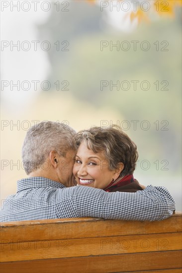 African couple hugging on park bench