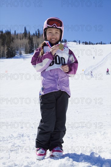 Mixed race girl showing off skiing medal