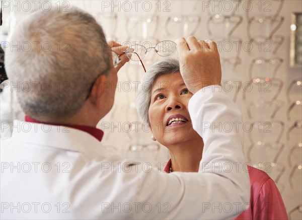 Chinese optician fitting woman's eyeglasses