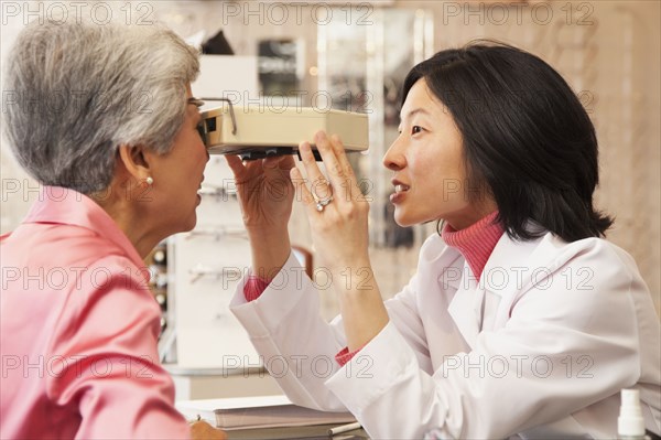 Korean optician giving woman eye exam