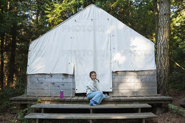 Mixed race girl sitting near tent