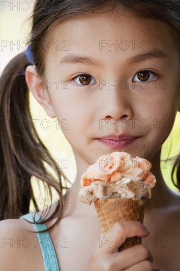 Mixed race girl eating ice cream cone