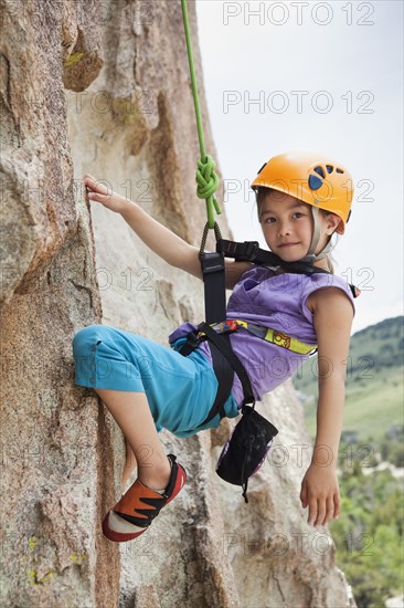 Mixed race girl rock climbing