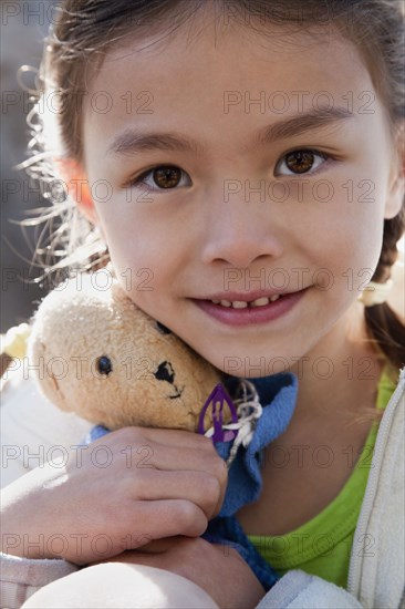 Mixed race girl holding teddy bear