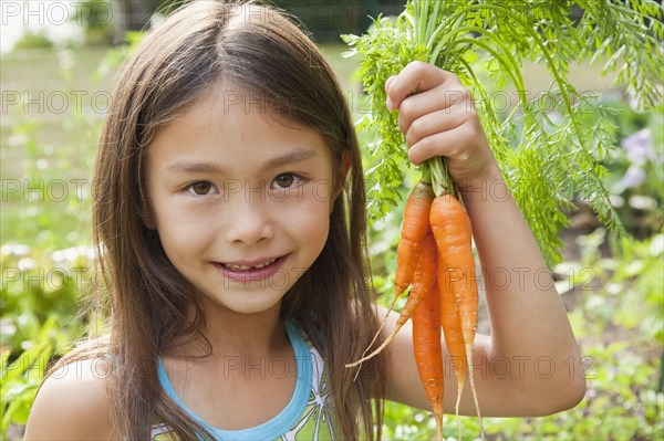 Mixed race girl holding carrots