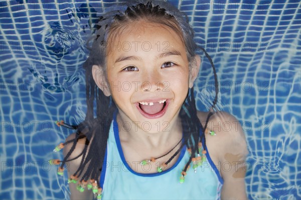 Mixed race girl floating in swimming pool