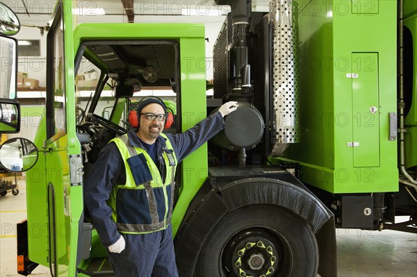 Pacific Islander man standing by garbage truck