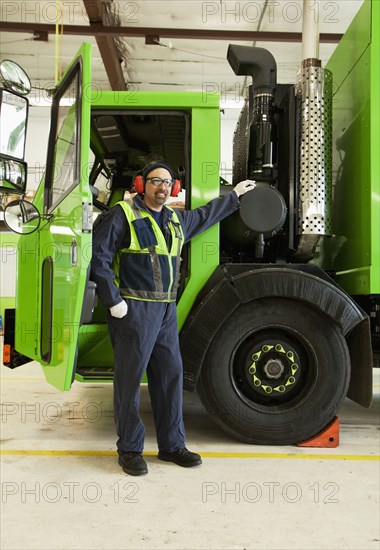 Pacific Islander man standing by garbage truck