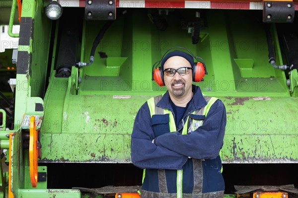 Pacific Islander man standing by garbage truck