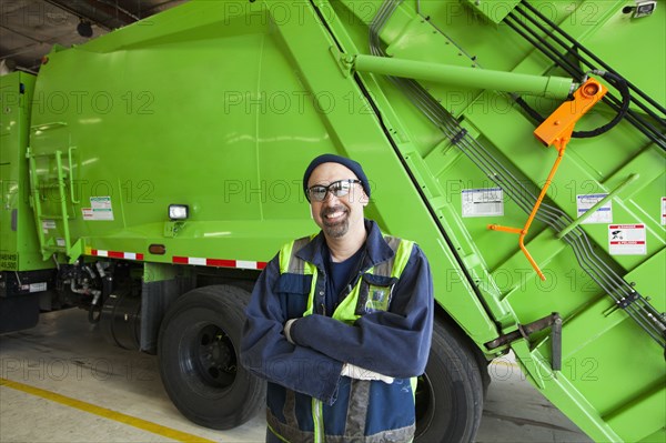 Pacific Islander man standing by garbage truck