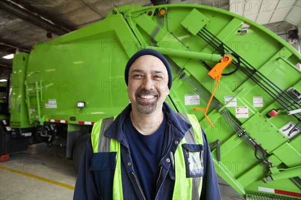 Pacific Islander man standing by garbage truck