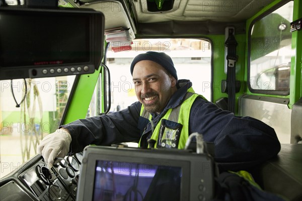 Pacific Islander man driving garbage truck