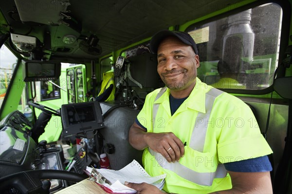 African American man driving garbage truck