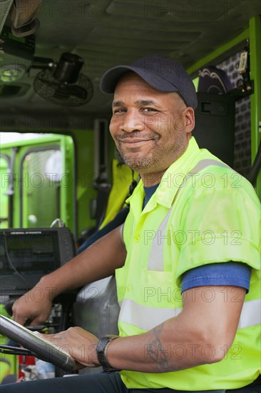 African American man driving garbage truck