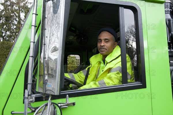 African American man driving garbage truck