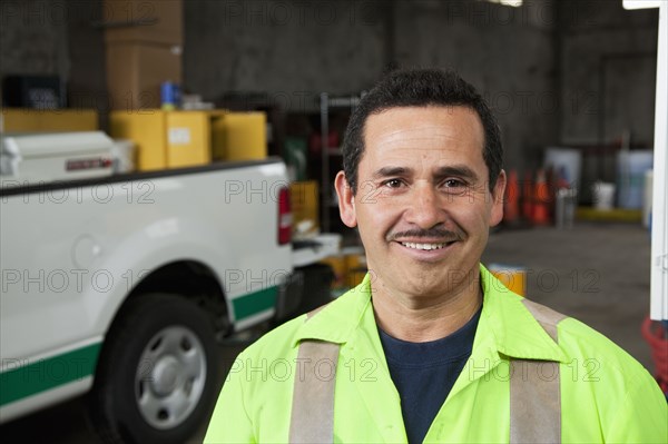 Hispanic sanitation worker smiling in garage