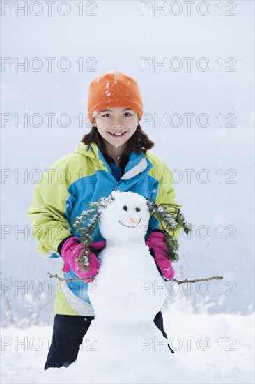 Mixed race girl building snowman