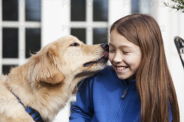 Golden retriever licking mixed race girl