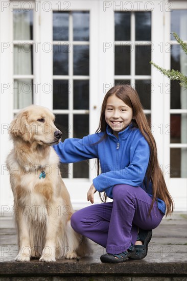 Mixed race girl petting Golden retriever