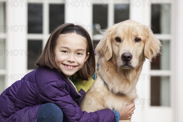 Mixed race girl hugging Golden retriever