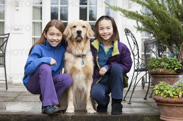 Mixed race girls hugging Golden retriever