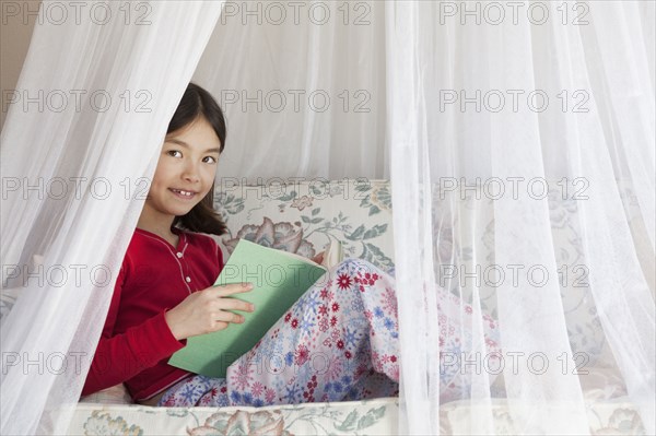 Mixed race girl reading on sofa