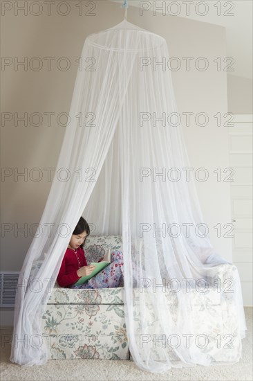 Mixed race girl reading on sofa