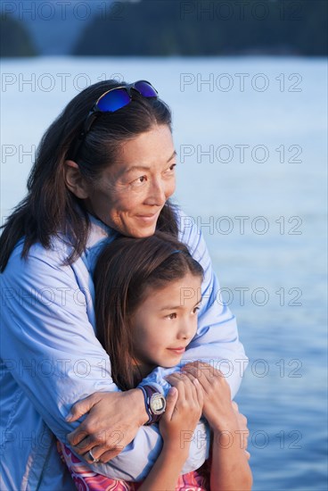 Mother and daughter hugging near lake