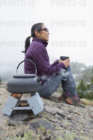 Japanese woman drinking coffee at campsite