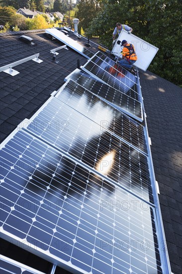 Caucasian men installing panels on roof