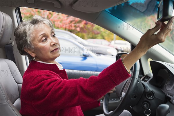 Mixed race woman adjusting car mirror