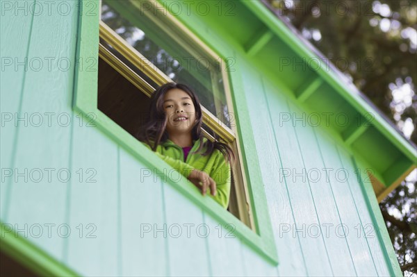 Mixed race girl leaning out window