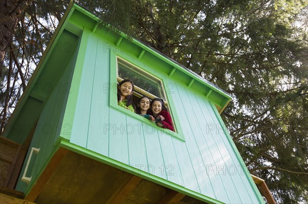 Girls leaning out tree house window