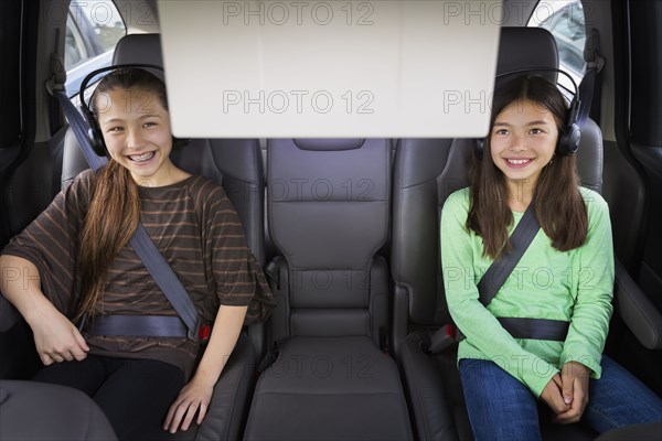 Mixed race girls watching television in backseat