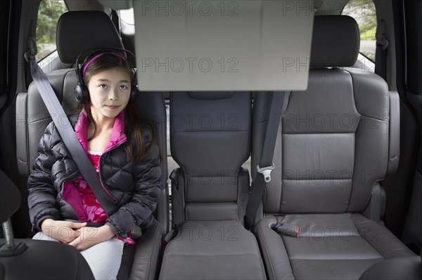 Mixed race girl watching television in backseat