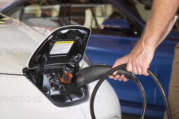 Close up of Caucasian man recharging electric car