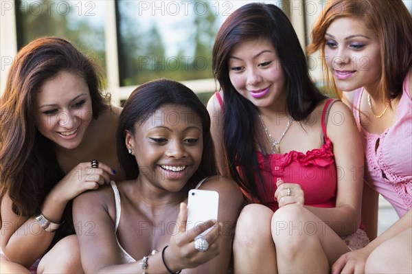 Teenage girls using cell phone together