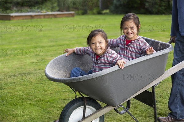 Twins with Down's Syndrome smiling in wheelbarrow