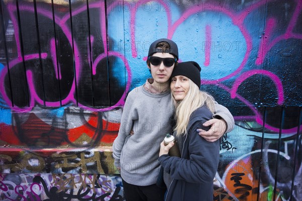 Caucasian mother and son hugging by graffiti wall