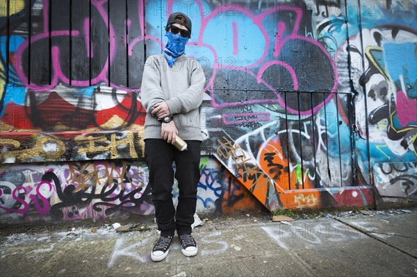 Caucasian teenage boy standing by graffiti wall