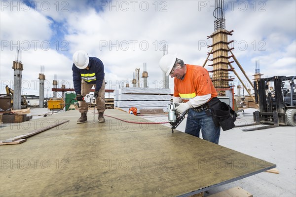 Caucasian workers drilling plant at construction site