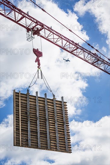 Crane lifting concrete wall form on construction site