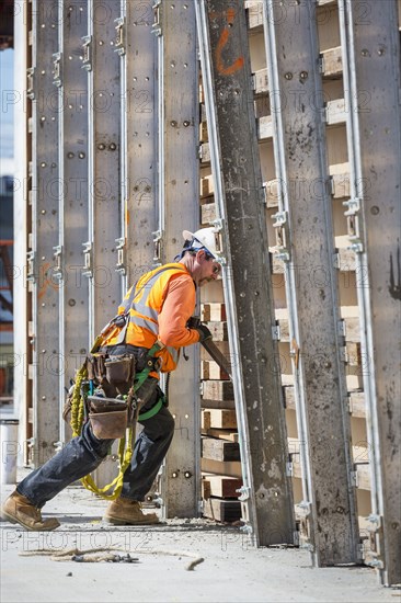 Caucasian worker pushing wall form at construction site