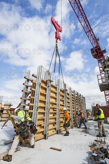 Caucasian workers operating crane at construction site