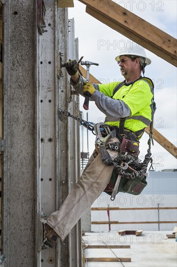 Caucasian worker hammering nails at construction site