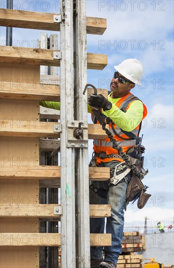 Hispanic worker holding hook at construction site