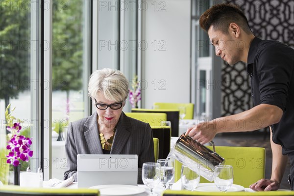 Waiter pouring water for customer in restaurant